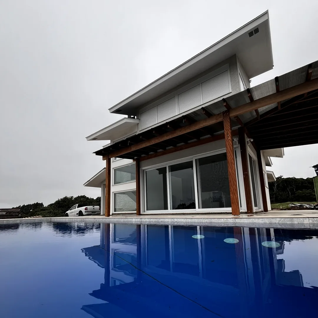 Casa com grandes portas de vidro refletida na piscina